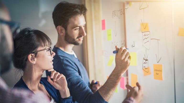 To ansatte jobber med strategi og utarbeider ideer på white board 