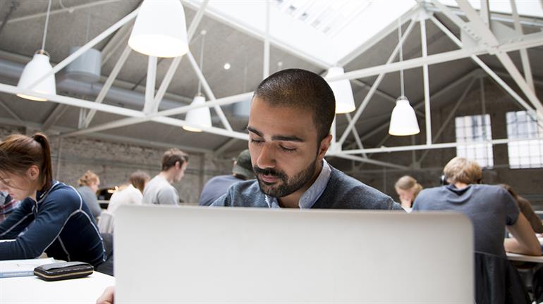 Student med laptop på lesesal