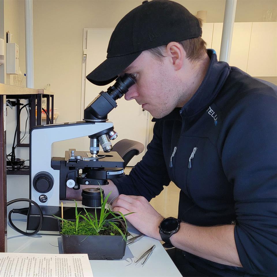 Tor-Eirik på lab med jordprøvar og mikroskop.